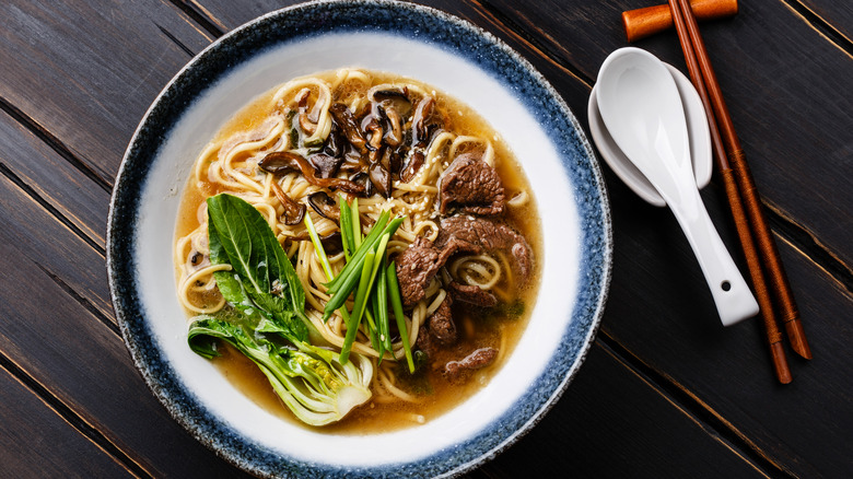 A bowl of beef ramen on a wooden table