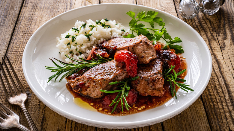 Pork with plums, rosemary, and rice on a plate