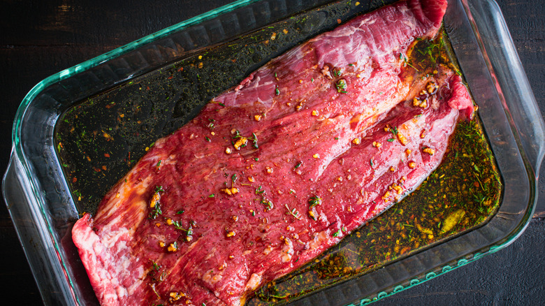 Flank steak rests in a marinade