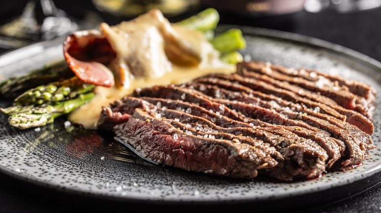 Sliced steak and asparagus on a dark plate