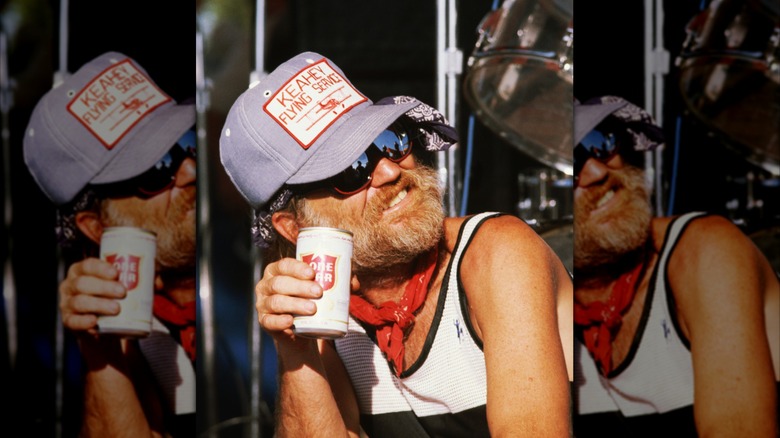 Willie Nelson holding a can of beer.
