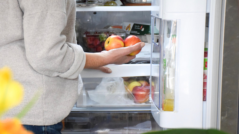 Person retrieving apples from crisper drawer