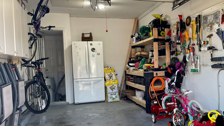 Fridge in a garage surrounded by tools
