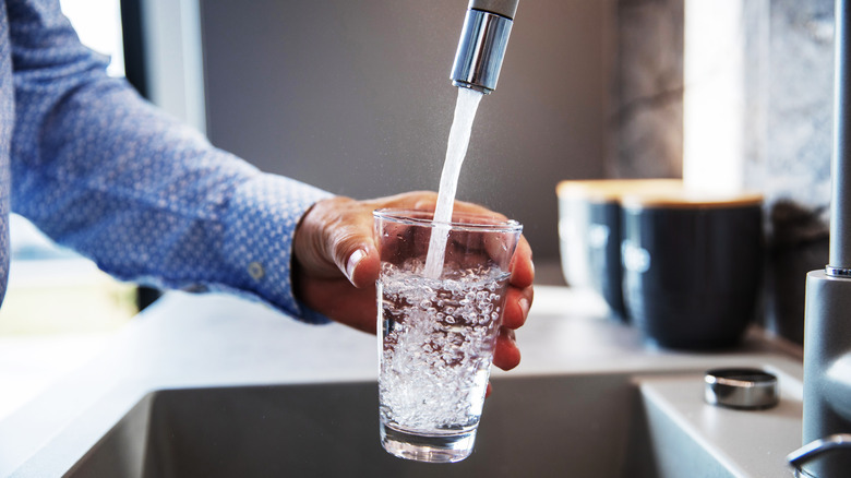 pouring glass of water from faucet