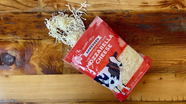 A bag of Trader Joe's Part-Skim Shredded Mozzarella Cheese spilling out onto a wooden table