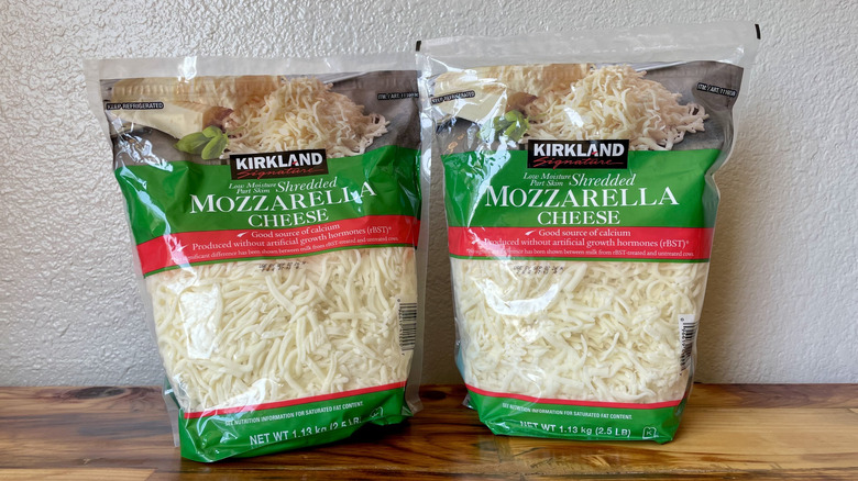 Two large bags of Kirkland Signature Part-Skim Shredded Mozzarella Cheese on a wooden table