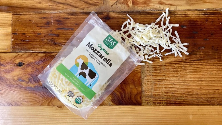 A bag of 365 by Whole Foods Market Organic Part-Skim Shredded Mozzarella Cheese spilling out onto a wooden table