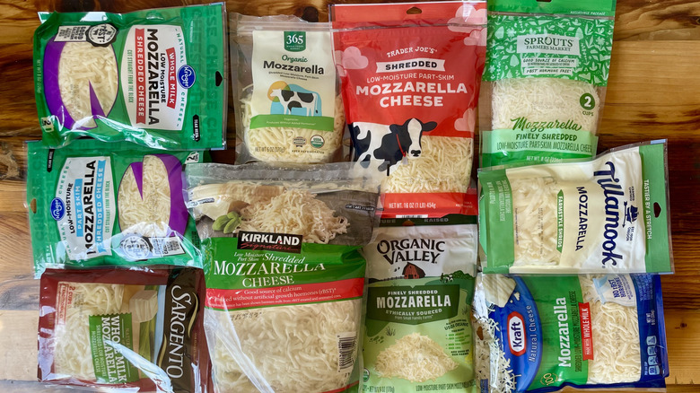 Various brands of shredded mozzarella cheese laid out on a wooden table top