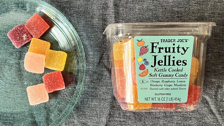 A handful of Trader Joe's Fruity Jellies on a glass plate next to a plastic, boxed package of Fruity Jellies