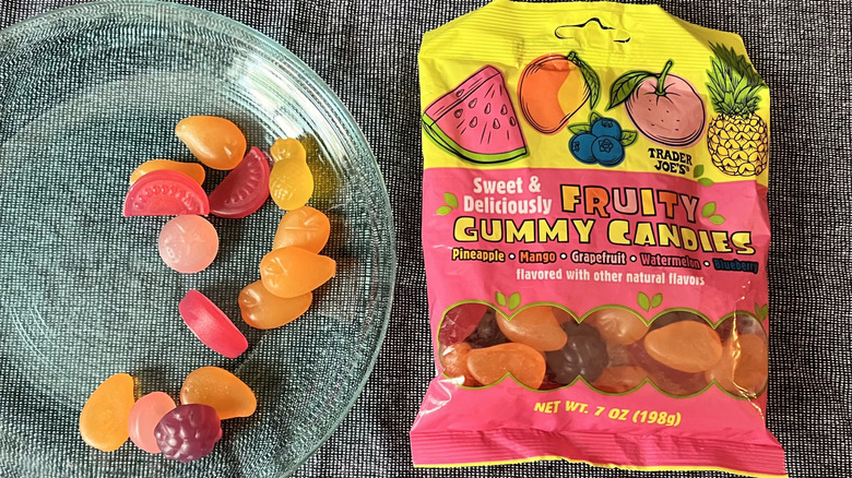 A handful of Trader Joe's Fruity Gummy Candies on a glass plate next to a bag of Fruity Gummy Candies