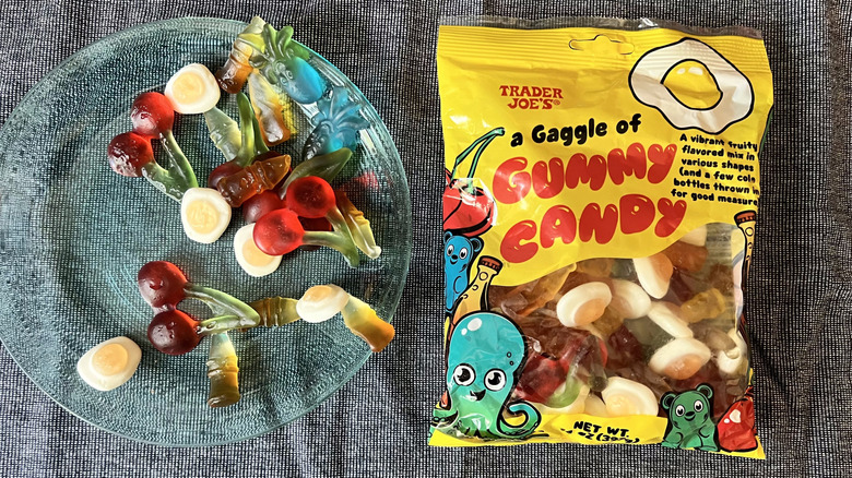 A handful of Trader Joe's Gaggle of Gummy Candy on a glass plate next to a bag of A Gaggle of Gummy Candy