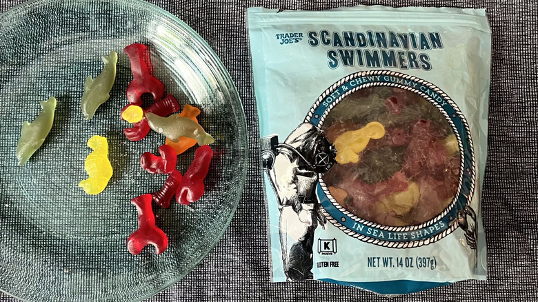 A handful of Trader Joe's Scandinavian Swimmers on a glass plate next to a bag of Scandinavian Swimmers