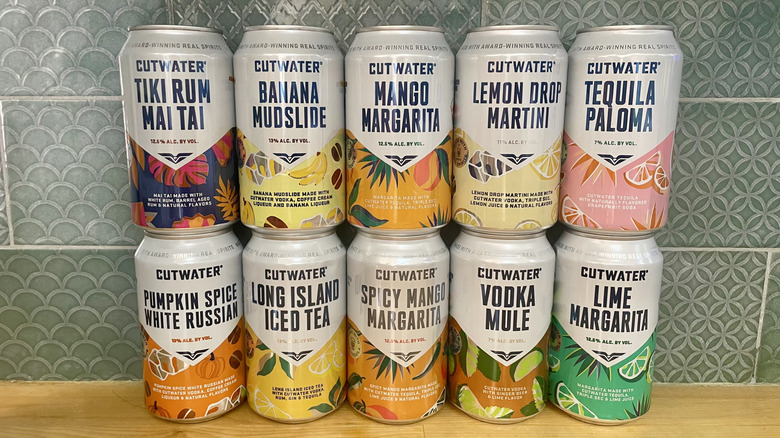 Various flavors of Cutwater canned cocktails lined up on a wooden countertop