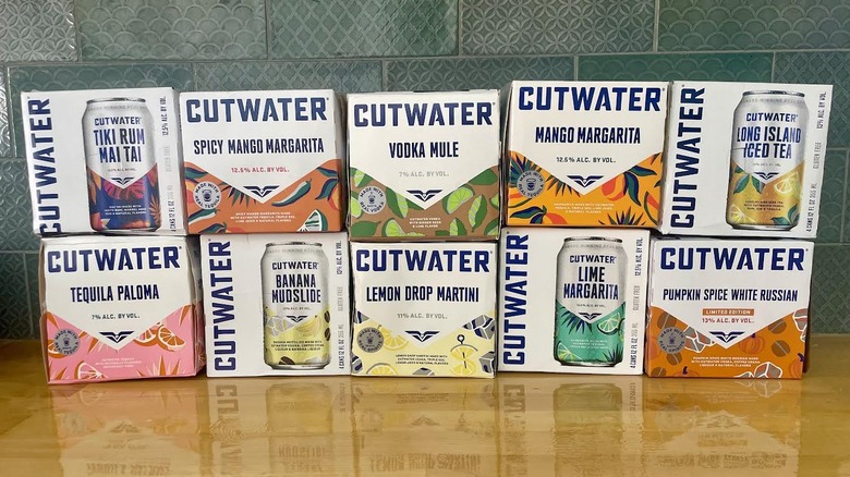 Cases of Cutwater canned cocktails in various flavors lined up on a wooden countertop