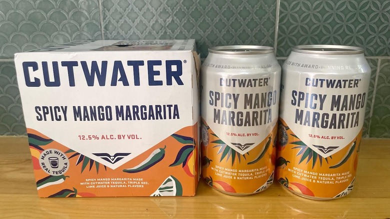 A box and two cans of Cutwater Spicy Mango Margarita cocktails