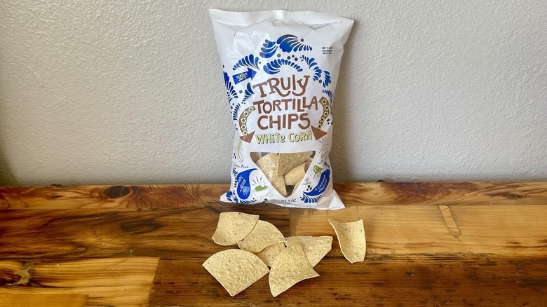 A bag of Truly White Corn Tortilla Chips on a wooden table top