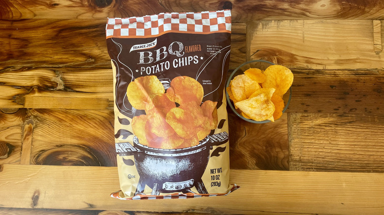 Overhead view of a bag and dish of BBQ Flavored Potato Chips on a wooden table top