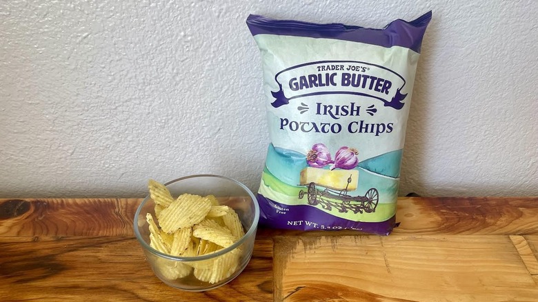 A bag and dish of Garlic Butter Irish Potato Chips on a wooden table top