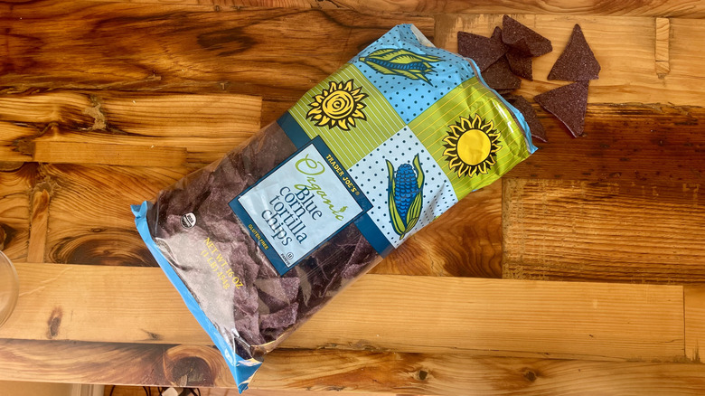 Overhead view of a bag of Organic Blue Corn Tortilla Chips spilling out onto a wooden table top