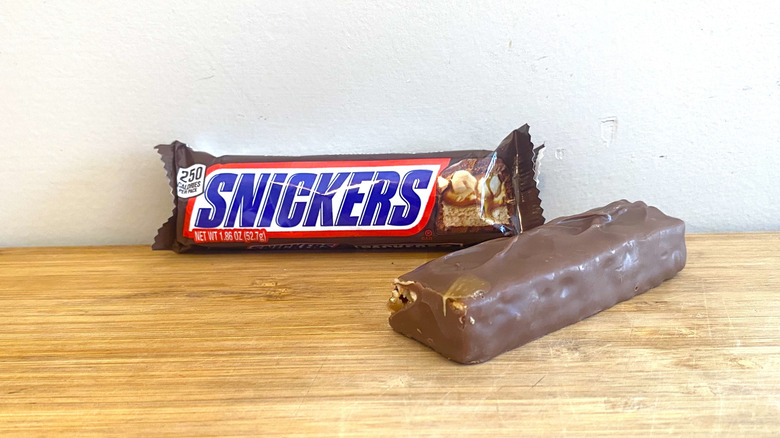 Wrapped Snickers bar with unwrapped Snickers bar on the right side