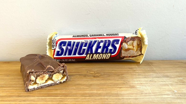 Wrapped Snickers Almond bar with halved Snickers Almond bar on the left side