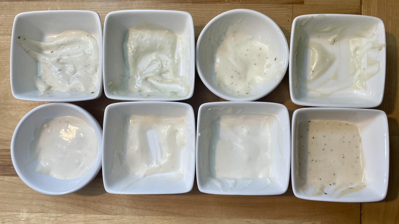 Overhead view of ramekins with various types of blue cheese dressing on wooden countertop