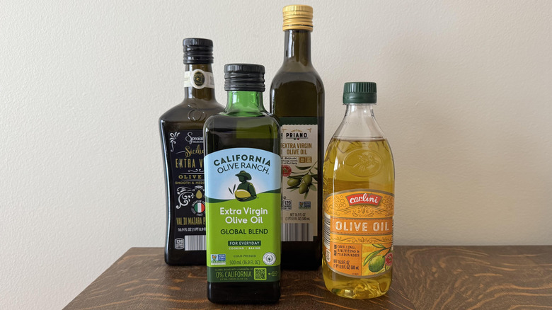 Four bottles of olive oil against white background