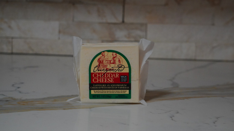 Block of Trader Joe's Unexpected Cheddar Cheese on marble countertop