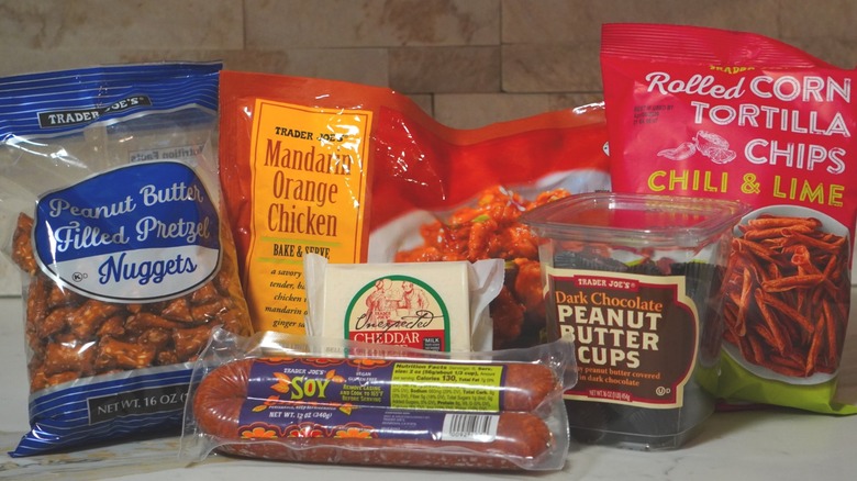 Trader Joe's Peanut Butter Filled Pretzel Nuggets, Soy Chorizo, Unexpected Cheddar Cheese, Mandarin Orange Chicken, Dark Chocolate Peanut Butter Cups, and Chili & Lime Rolled Corn Tortilla Chips arranged on countertop