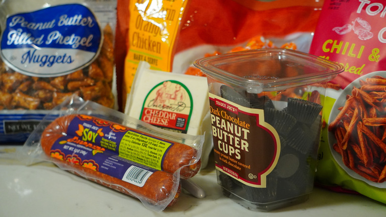 Side view of Trader Joe's Peanut Butter Filled Pretzel Nuggets, Soy Chorizo, Unexpected Cheddar Cheese, Mandarin Orange Chicken, Dark Chocolate Peanut Butter Cups, and Chili & Lime Rolled Corn Tortilla Chips