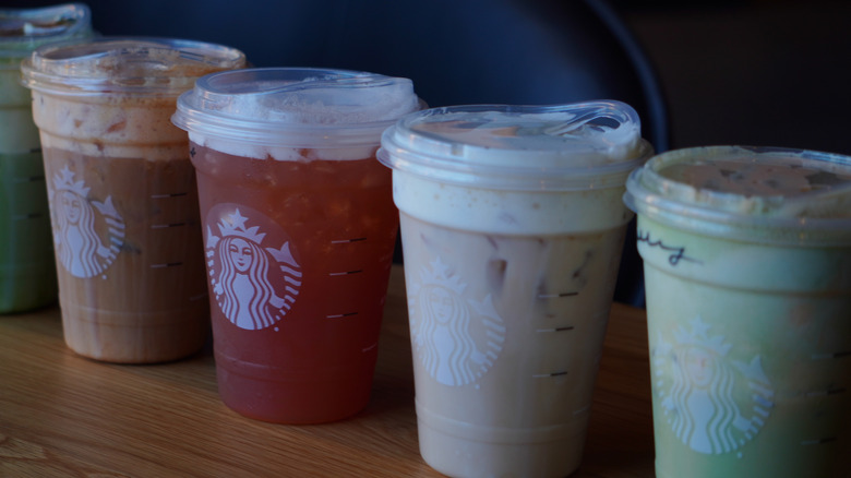 Side view of Starbucks' Iced Pumpkin Cream Shaken Espresso, Iced Chaider, Iced Banana Bread Chai, and Iced Pumpkin Cream Matcha (left to right).