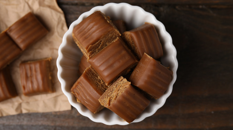 Homemade caramel candies in a bowl next to candies on parchment paper