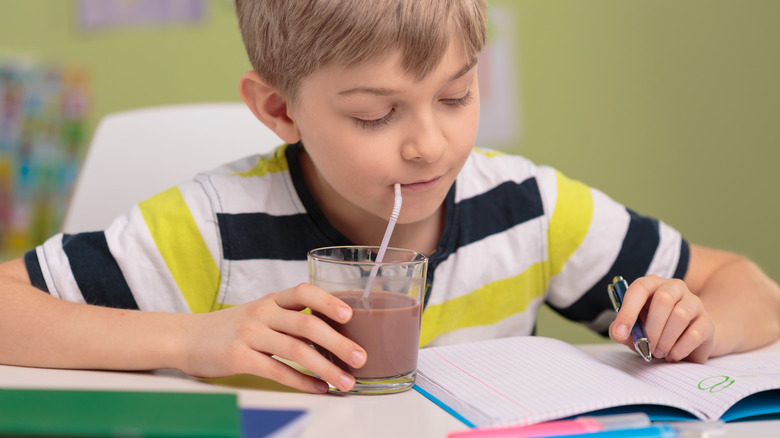 kid drinking chocolate milk and doing school work