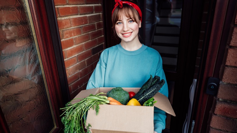 woman carrying groceries in a box