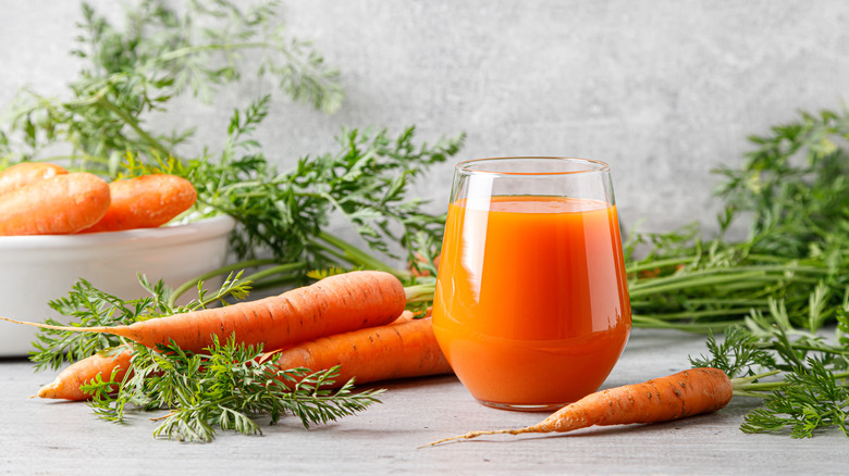 Whole carrots and glass of carrot juice