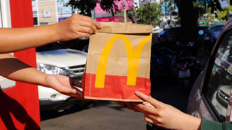 Working handing a McDonald's bag to a customer in the drive thru