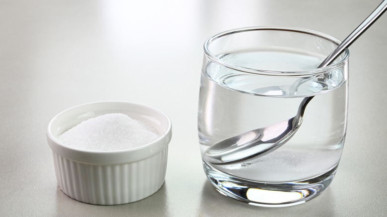 glass of water with container of salt