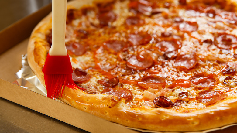 Pizza being brushed with oil