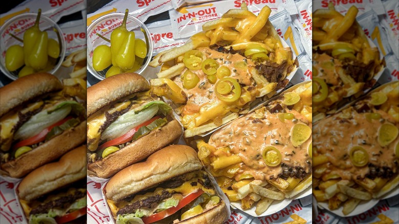 Two In-N-Out burgers with two animal-style sides of fries, packets of spread, and peppers.
