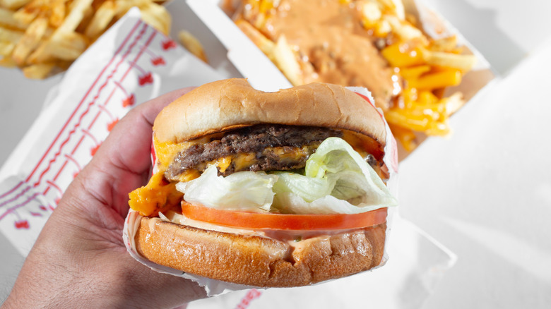 Someone holds a double-double over some animal-style fries at In-N-Out.