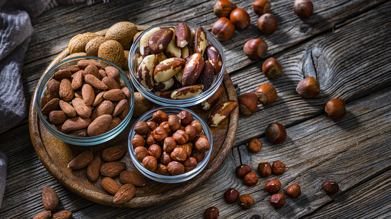 Bowls of almonds, hazelnuts, and Brazil nuts on wood table