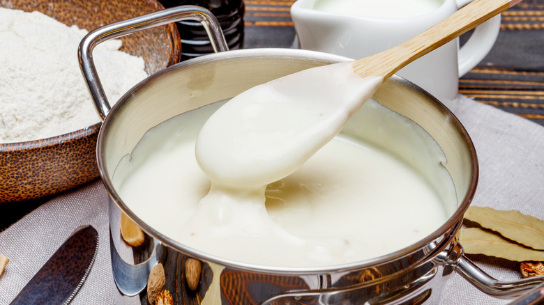 Béchamel sauce in pot with spoon