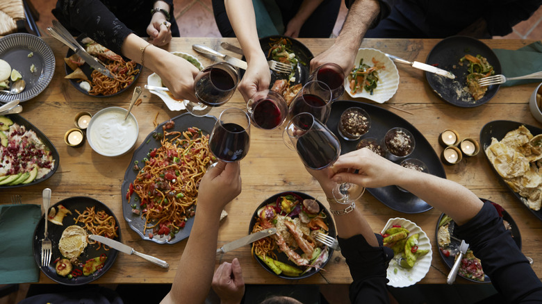 Friends clinking wine glasses at a dinner party table