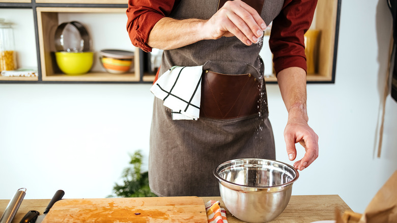 Man sprinkling salt into bowl