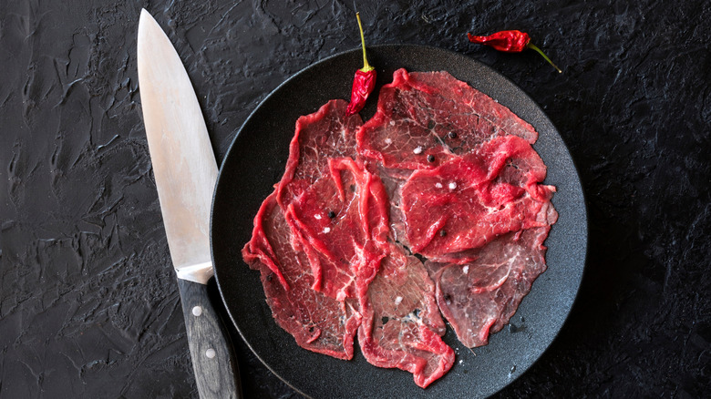 Thinly sliced beef carpaccio with knife