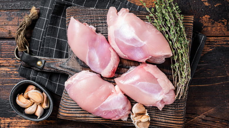 skinless chicken thighs on wooden board
