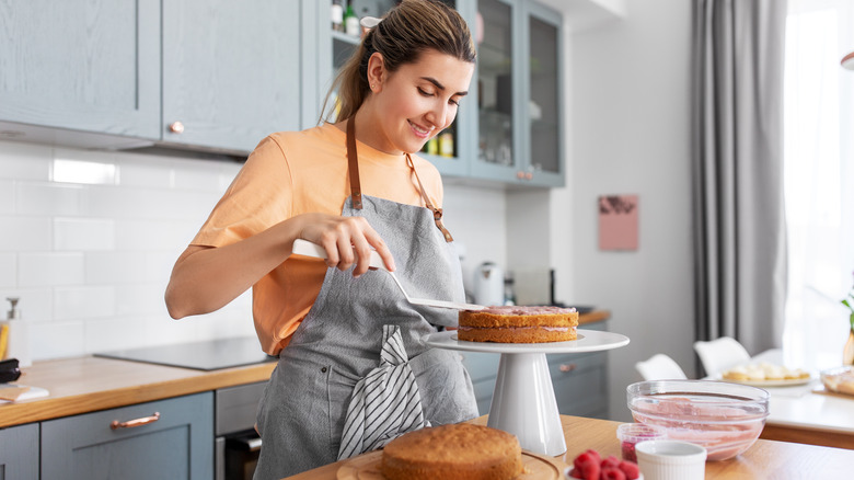 person frosting cake layers