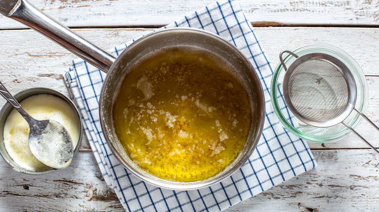 A pot of liquid clarified butter next to bowl of milk solids