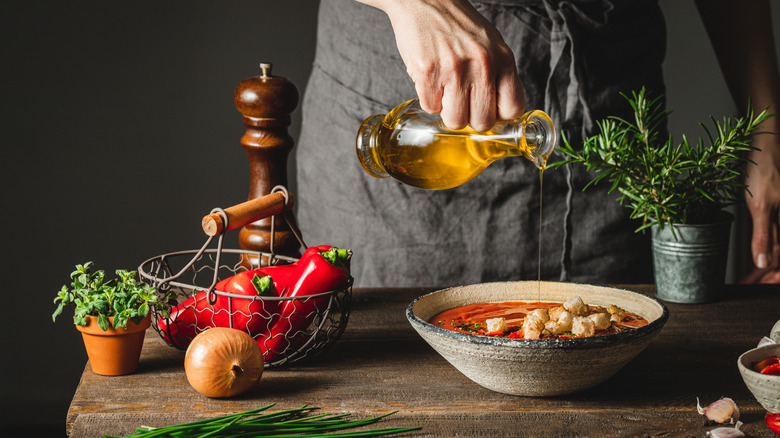 woman adding olive oil to soup