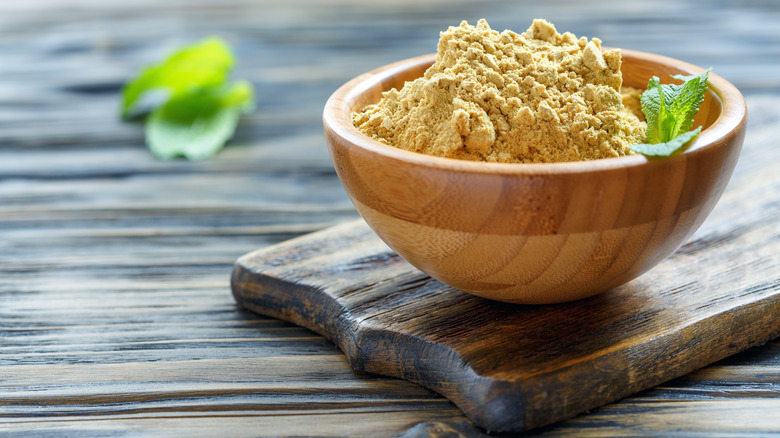 ground mustard in a wooden bowl on a wooden board